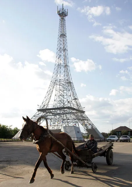 Russia: A horse and cart passes by a 50-meter copy of the Eiffel tower in the village Parizh (Paris)  59 miles southeast of Russia's Siberian city of Magnitogorsk, July 15, 2005. The village bears the name of the French capital since its foundation in the 19th century by Russian Cossaks who had returned from Paris after defeating Napoleon army. The tower was built by the local communication company as a tower for their equipment and a possible tourist attraction. (Photo by Sergei Karpukhin/Reuters)