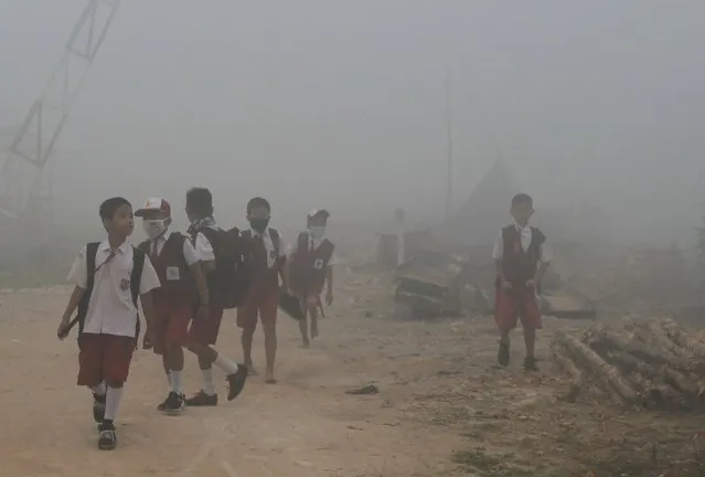 Schoolchildren make their way to school as haze from forest fires blankets Palembang on October 14, 2019. Forest fires raging across Indonesia have sent air quality levels across Southeast Asia plummeting as they belch out emissions that aggravate global warming. (Photo by Abdul Qodir/AFP Photo)
