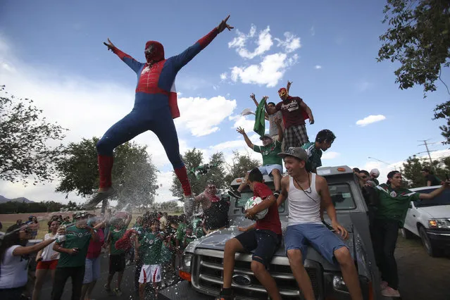 A Mexican soccer fan, dressed in a Spiderman costume, jumps from a vehicle as he celebrates Mexico's 2014 World Cup soccer match win over Croatia, in Ciudad Juarez June 23, 2014. (Photo by Jose Luis Gonzalez/Reuters)