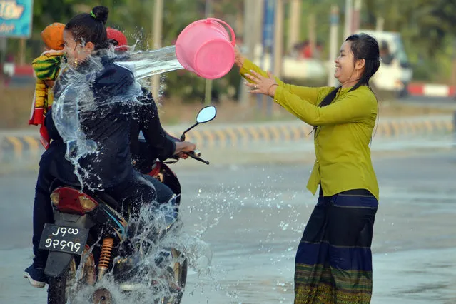 A woman throws water at passing motorists during celebrations for the Thingyan festival, also known as the Buddhist New Year, in Naypyidaw, Myanmar on April 16, 2019. (Photo by Thet Aung/AFP Photo)