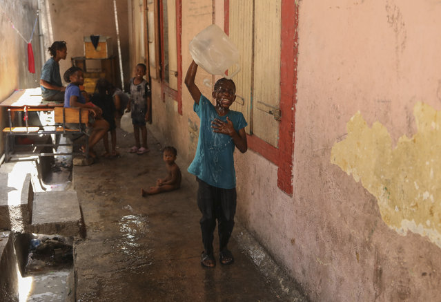 A boy pours a jug of water on his head at a school that serves as a shelter for people displaced by gang violence in Port-au-Prince, Haiti, Tuesday, August 13, 2024. (Photo by Odelyn Joseph/AP Photo)