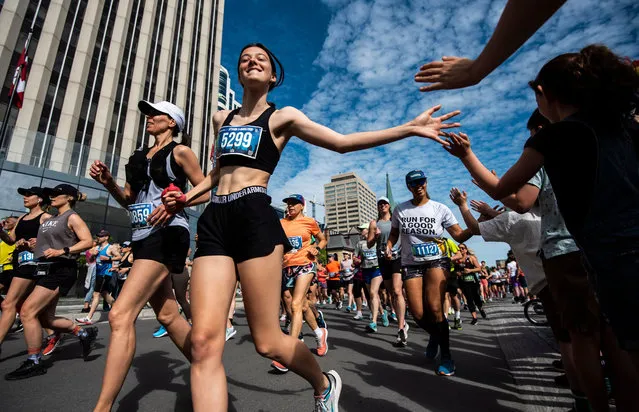 Runners high-five children cheering from the sidewalk as they begin the half marathon during the Ottawa Race Weekend, which returned from a two-year hiatus due to the COVID-19 pandemic in Ottawa, Canada on Sunday, May 29, 2022. (Photo by Canadian Press/Rex Features/Shutterstock)