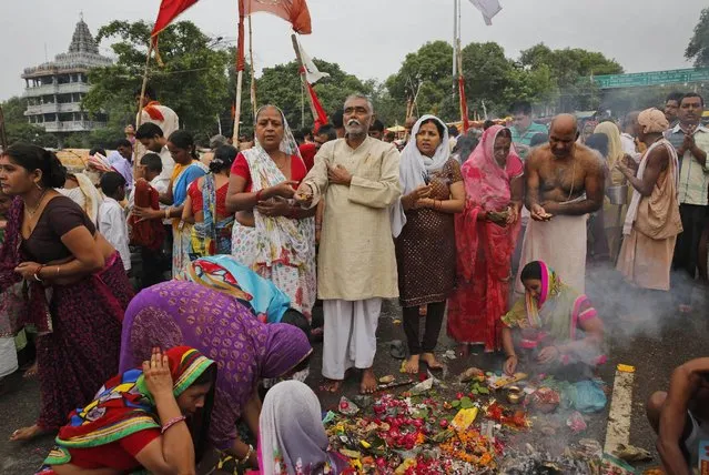 Hindu devotees pray after taking a holy dip at Sangam, the confluence of the Rivers Ganges, Yamuna the mythical Saraswati, on the occasion of Guru Purnima, or full moon day dedicated to the Guru, in Allahabad, India, Friday, July 31, 2015. (Photo by Rajesh Kumar Singh/AP Photo)