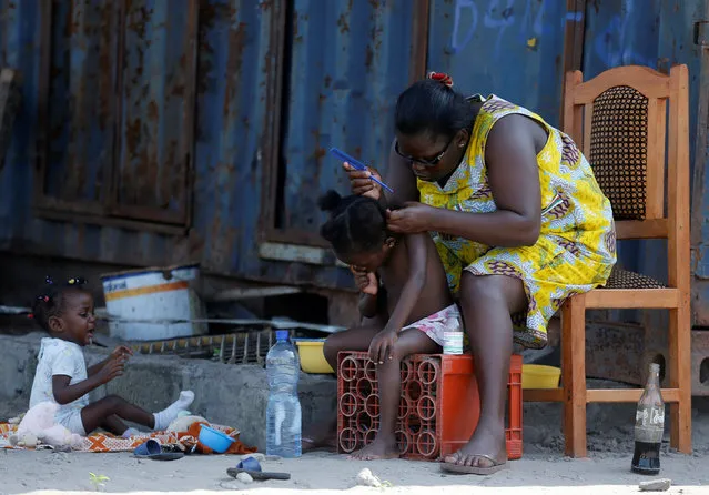 A woman is seen hairdressing her kids in front of her home near Stade de Port Gentil, Gabon January 29, 2017. (Photo by Amr Abdallah Dalsh/Reuters)