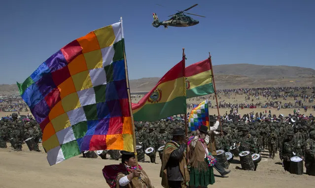 Aymara indigenous men and women carry Bolivian and Wiphala flags during a military parade commemorating the 192 anniversary of Bolivia's army in Kjasina, Bolivia, Monday, August 7, 2017. Years ago the government starting holding its annual, national celebrations away from the capital, to get residents in the interior to participate as well. (Photo by Juan Karita/AP Photo)