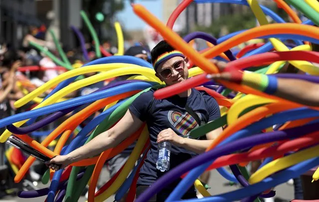 People walk the parade route with colorful balloons during the Pride Parade on Chicago's North side on Sunday, June 26, 2022. (Photo by Chris Sweda/Chicago Tribune via AP Photo)
