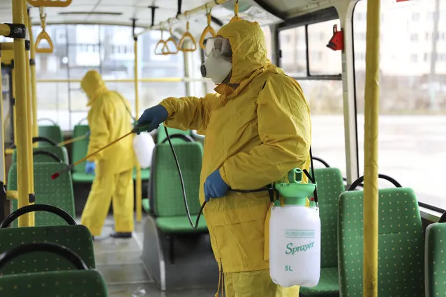 Employees wearing protective gear spray disinfectant to sanitize a passenger bus as a preventive measure against the coronavirus in Lviv, Ukraine, Tuesday, March 3, 2020. Ukrainian Chief sanitary and epidemiological doctor Viktor Liashko has just reported its first confirmed case of the new COVID-19 coronavirus, saying a man who recently arrived from Italy was diagnosed with the virus. (Photo by Mykola Tys/AP Photo)
