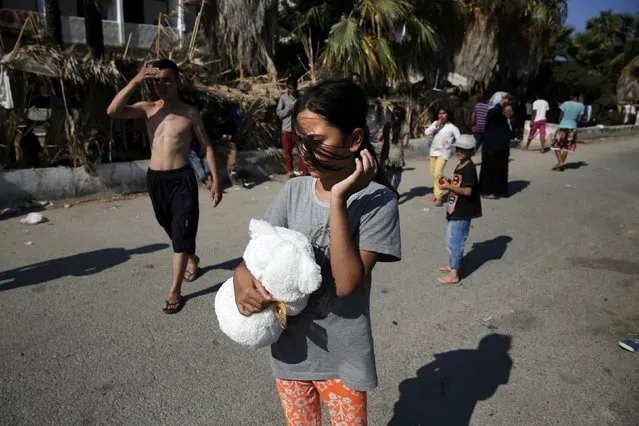 A young migrant girl holds a teddy bear offered by volunteers of the organisation “Solidarity Kos” outside Captain Elias, a derelict hotel where migrants find shelter on the Greek island of Kos, August 17, 2015. (Photo by Alkis Konstantinidis/Reuters)