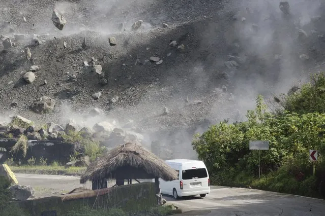 Boulders fall as a vehicle negotiates a road during an earthquake in Bauko, Mountain Province, Philippines on Wednesday July 27, 2022. A strong earthquake left some people dead and injured dozens in the northern Philippines on Wednesday, where the temblor set off small landslides and damaged buildings and churches and prompted terrified crowds and hospital patients in the capital to rush outdoors. One passenger was injured after a boulder hit the vehicle. (Photo by Harley Palangchao/AP Photo)