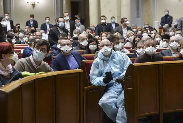 Ukrainian lawmakers wearing face masks to protect against coronavirus attend an extraordinary parliamentary session in Kyiv, Ukraine, Monday, March 30, 2020. Ukraine has been under quarantine since March 12. (Photo by AP Photo/Stringer)