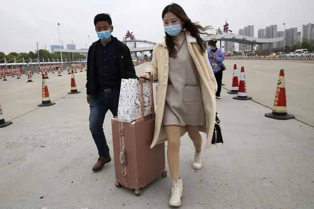 In this Thursday, April 2, 2020, photo, a woman walks from the expressway gate at the border of Wuhan city in central China's Hubei province. Millions of Chinese workers are streaming back to factories, shops and offices but many still face anti-coronavirus controls that add to their financial losses and aggravation. In Wuhan police require a health check and documents from employers for returning workers. (Photo by Ng Han Guan/AP Photo)