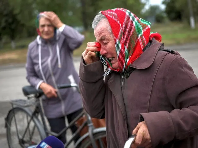 Local residents react as they wait for a car distributing humanitarian aid, as Russia's attack on Ukraine continues, in the village of Verbivka, recently liberated by Ukrainian Armed Forces, in Kharkiv region, Ukraine on September 13, 2022. (Photo by Gleb Garanich/Reuters)