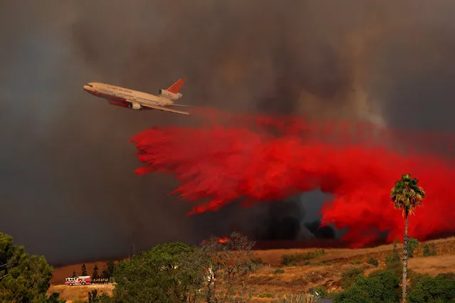 A DC-10 aircraft drops fire retardant on a wind driven wildfire in Orange, California, U.S., October 9, 2017. (Photo by Mike Blake/Reuters)