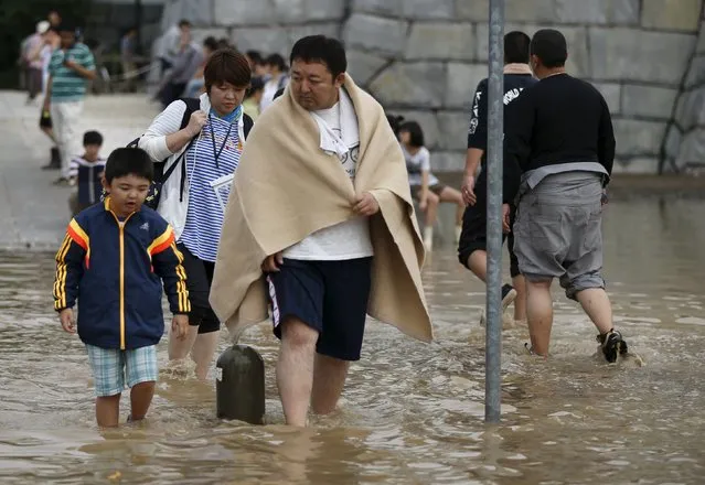 Local residents wade through a residential area flooded by the Kinugawa river, caused by typhoon Etau, in Joso, Ibaraki prefecture, Japan, September 11, 2015. (Photo by Issei Kato/Reuters)