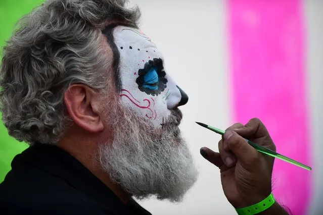 A man has his face painted during celebrations in the framework of the Day of the Dead at the Hermanos Rodriguez racetrack in Mexico City, on October 26, 2017 ahead of the week-end's Mexican Formula One Grand Prix. (Photo by Pedro Pardo/AFP Photo)
