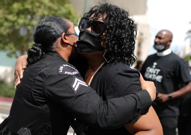 A demonstrator hugs a police officer during a protest against the death in Minneapolis police custody of George Floyd, outside LAPD headquarters in Los Angeles, California, U.S. June 2, 2020. (Photo by Lucy Nicholson/Reuters)