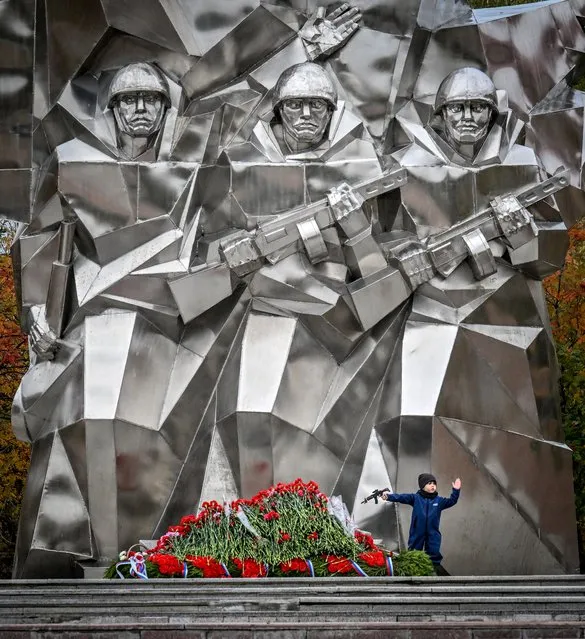 A boy holds a toy machinegun as he stands next to a monument with fresh flowers to Podolsk's cadets died in 1941 during World War II in the town of Podolsk some 40 kilometres outside Moscow on October 6, 2022. Podolsk cadets – cadets of the Podolsk artillery and rifle military schools, who were alerted on October 5, 1941 to the defence of Moscow in the initial period of World War II. (Photo by Yuri Kadobnov/AFP Photo)