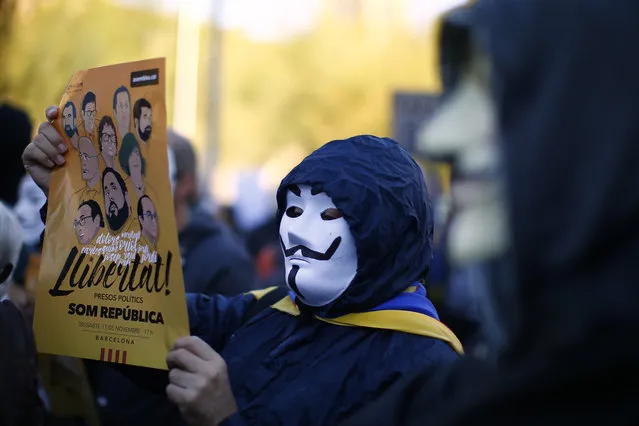 A demonstrator holds a banner that reads in Catalan: “Freedom for the Political Prisoners”, gather during a protest against the decision of a judge to jail ex-members of the Catalan government at the University square in Barcelona, Spain, Sunday, November 5, 2017. A Spanish judge issued an international arrest warrant on Friday for former members of the Catalan Cabinet who were last seen in Brussels, including the ousted separatist leader Carles Puigdemont, who said he was prepared to run for his old job even while battling extradition in Belgium. (Photo by Manu Fernandez/AP Photo)