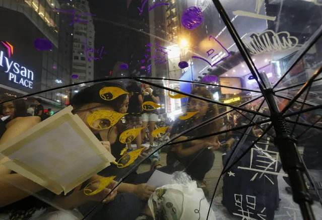 A protester draws on an umbrella with Chinese characters reading “true elections” (in white) during a rally blocking the main road at Causeway Bay shopping district in Hong Kong September 30, 2014. (Photo by Bobby Yip/Reuters)