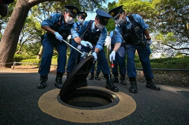 Police officers inspect a manhole near the Budokan Hall, venue for the September 27 state funeral of former Japanese prime minister Shinzo Abe, in Tokyo on September 26, 2022. (Photo by Kazuhiro Nogi/AFP Photo)