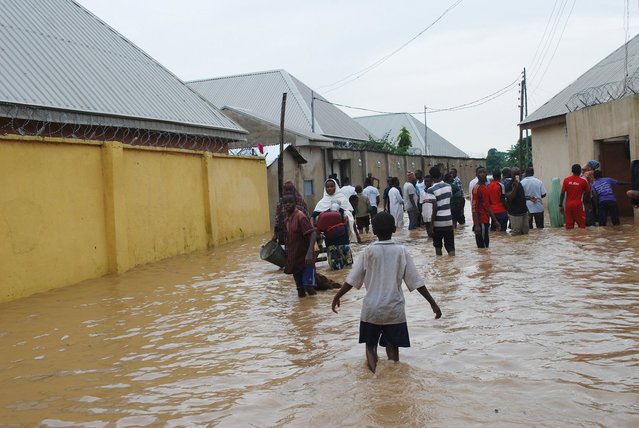 People wade through water after a heavy downpour, which resulted in flooding and displacement of people, in Banawa district, Kaduna, September 21, 2015. (Photo by Reuters/Stringer)