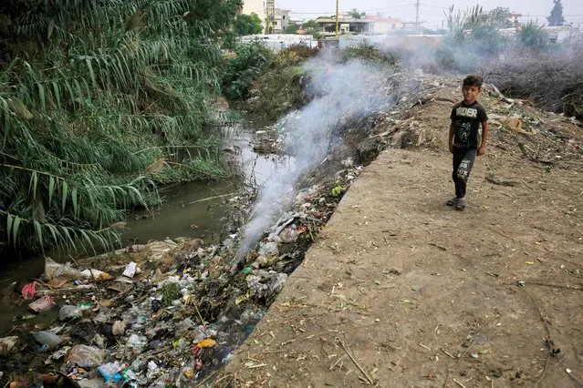 A child stands next to a pile of garbage at a make-shift camp for Syrian refugees in Talhayat in the Akkar district in north Lebanon on October 26, 2022. (Photo by Ibrahim Chalhoub/AFP Photo)
