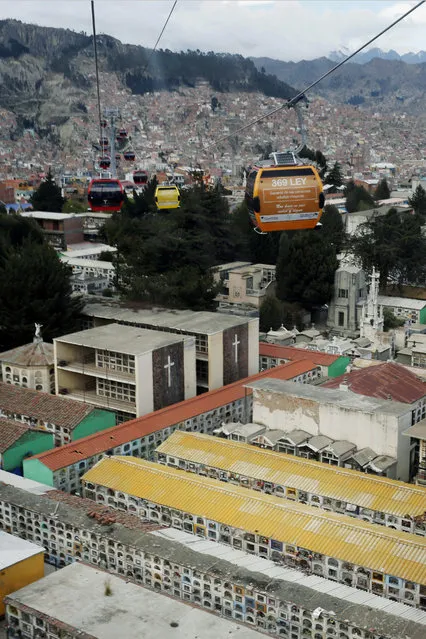 In this Oct. 9, 2014 photo, people use cable cars to commute over buildings containing crypts at a cemetery, in La Paz, Bolivia. Cemetery overcrowding is an issue that resonates around the world, particularly in its most cramped cities and among religions that forbid or discourage cremation. (AP Photo/Enric Marti)