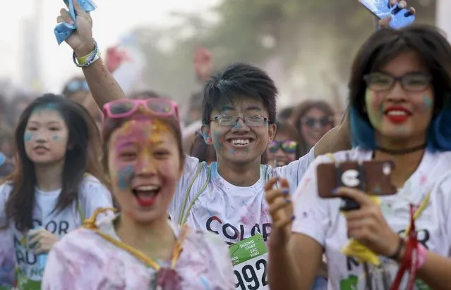 Participants covered by colored powder gesture as they compete in The Color Run, a five-kilometre untimed race, in Hanoi, Vietnam September 26, 2015. (Photo by Reuters/Kham)