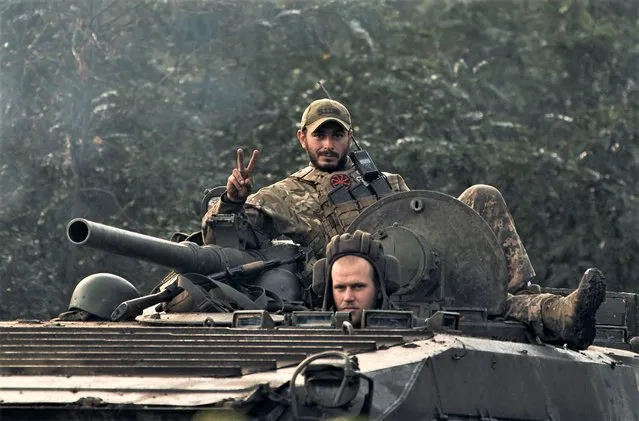 A Ukrainian soldier shows a V-sign atop a vehicle in Izium, Kharkiv region, Ukraine, Tuesday, September 13, 2022. Ukrainian troops piled pressure on retreating Russian forces Tuesday, pressing deeper into occupied territory and sending more Kremlin troops fleeing ahead of the counteroffensive that has inflicted a stunning blow on Moscow's military prestige. (Photo by Kostiantyn Liberov/AP Photo)