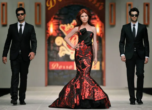 In this photo taken Friday, June 8, 2012, Russian ex-spy Anna Chapman, center, walks a Turkish catwalk flanked by two men posing as secret service agents at a fashion show in Antalya, Turkey. The 30-year-old Chapman was deported from the United States in 2010 along with nine other Russian sleeper agents. (Photo by AP Photo/Stringer)