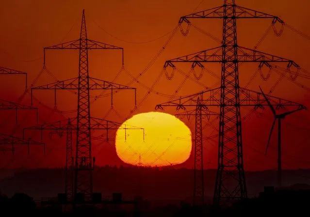 The sun rises behind power poles in the outskirts of Frankfurt, Germany, Sunday, May 15, 2022. (Photo by Michael Probst/AP Photo)