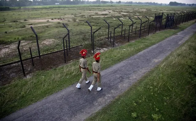 In this  Friday, September 2, 2016 photo, Indian Border Security Force personnel patrol near a fence on the India- Bangladesh border at Thakuranbari village, in the northeastern Indian state of Assam. Chief Minister of Assam state Sarbananda Sonowal has sought help from the central government in sealing the porous border, one of the core issues of the ruling Bharatiya Janata Party's election campaign in Assam. (Photo by Anupam Nath/AP Photo)
