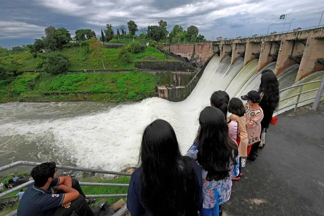 People watch the Rawal Dam after the spillway opened due to heavy monsoon rains, in Islamabad on August 31, 2020. More than 100 Pakistanis died in August because of the monsoon, which has also destroyed more than 1,000 homes. (Photo by Aamir Qureshi/AFP Photo)