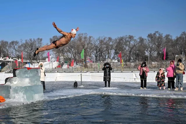 A man dives into a pool cut into the frozen Songhua river in Harbin, in China's northeastern Heilongjiang province on January 5, 2023, ahead the opening ceremony of the 39th Harbin China International Ice and Snow Festival. (Photo by Hector Retamal/AFP Photo)