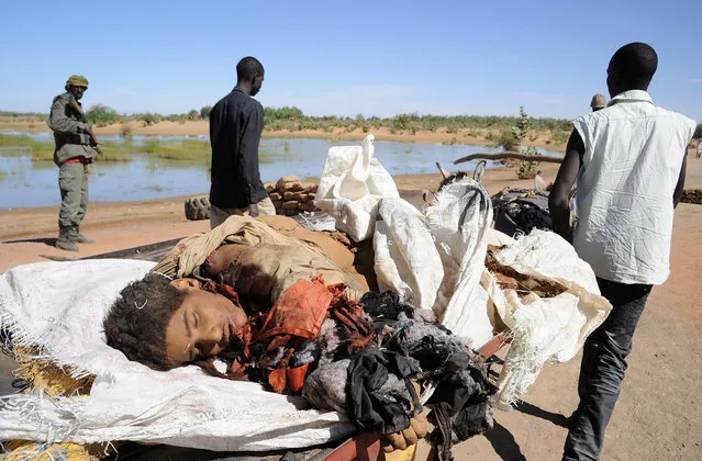 Malians carry the mangled corpse of a suicide bomber who blew himself up near a group of Malian soldiers in the northern city of Gao, where Islamist rebels driven from the town have resorted to guerrilla attacks, on on February 8, 2013. The act marked the first suicide attack in the embattled west African nation since the start of a French-led offensive to oust the Islamists from Mali's north. (Photo by Pascal Guyot/AFP Photo/The Atlantic)