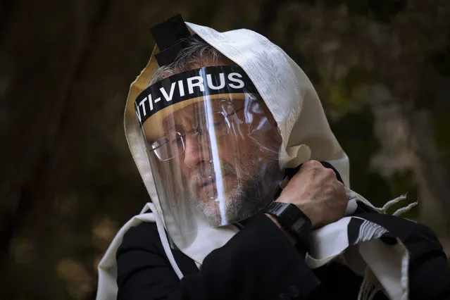 An Ultra-Orthodox Jewish man wears a face mask during a morning prayer next to his house as synagogues are limited to twenty people during a nationwide three-week lockdown to curb the spread of the coronavirus, in Bnei Brak, Israel, Thursday, September 24, 2020. Israel moved to further tighten its second countrywide lockdown as coronavirus cases continued to soar. The Cabinet voted to close all nonessential businesses, including open-air markets. Prayers and political demonstrations would be limited to open spaces and no more than 20 people, and participants would not be able to travel more than a kilometer (0.6 miles) from home for either. (Photo by Oded Balilty/AP Photo)