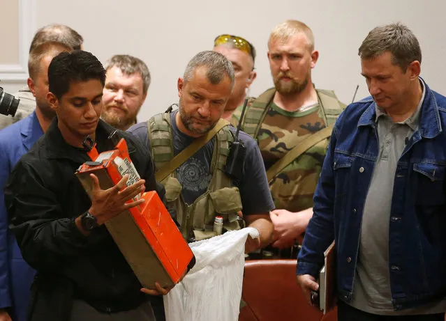 A Malaysian expert (L) examines a black box belonging to Malaysia Airlines flight MH17 during its handover from pro-Russian separatists, in Donetsk July 22, 2014. (Photo by Maxim Zmeyev/Reuters)