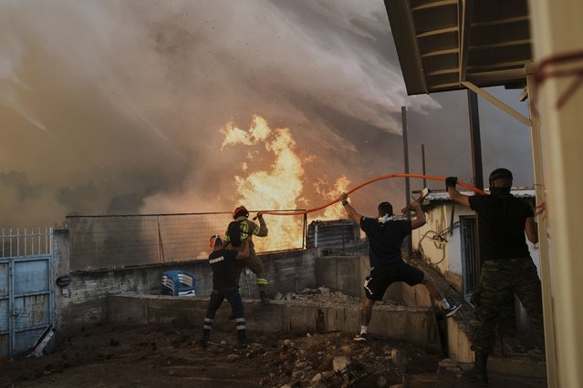 A firefighter and men try to control the fire approaching a house during a wildfire in Patras city, western Greece, Wednesday, August 13, 2025. (Photo by Thanassis Stavrakis/AP Photo)