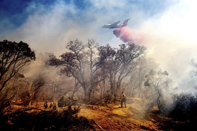 An air tanker drops retardant on the Olinda Fire in Anderson, Calif., Sunday, October 25, 2020. The blaze was one of four fires burning near Redding that firefighters scrambled to stop as high winds buffeted Northern California. (Photo by Noah Berger/AP Photo)