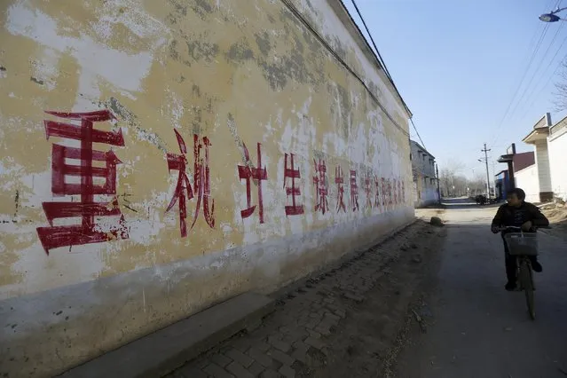 A resident rides a bicycle past a slogan on the wall which partially read "pay attention to One Child Policy and seek developments", at a village in Handan, Hebei province, China, December 12, 2014. China will ease family planning restrictions to allow all couples to have two children after decades of the strict one-child policy, the ruling Communist Party said on October 29, 2015, a move aimed at alleviating demographic strains on the economy. (Photo by Reuters/Stringer)