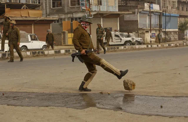 An Indian policeman removes a piece of rock placed by protestors to block traffic  during a protest against the killing of a youth in Srinagar, Indian controlled Kashmir, Sunday, November 8, 2015. One demonstrator was killed Saturday, during clashes with government troops shortly after Prime Minister Narendra Modi ended a daylong visit in which he promised $12 billion in aid to the troubled region. (Photo by Mukhtar Khan/AP Photo)