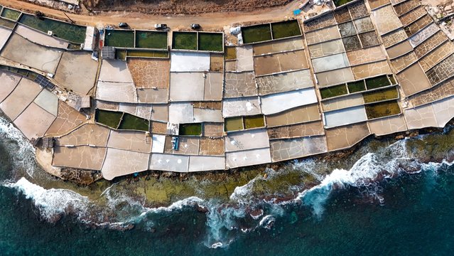 An aerial view taken with a drone shows salt evaporation ponds in the coastal town of Anfeh, Lebanon, 22 August 2025. George Sulaiman inherited the family sea salt business in 2013 and modernized it to produce a wider range of products, including coarse salt, magnesium salt, magnesium oil, Japanese nigari salt, and fleur de sel, in an operation running over 4,000 square meters and has an annual production of 60 tons of salt. The production of sea salt is a long-standing artisanal tradition in Anfeh, which includes drawing seawater into shallow, concrete-lined basins, where it evaporates over several months due to the sun and wind, leaving behind salt crystals that are subsequently harvested. (Photo by Wael Hamzeh/EPA)