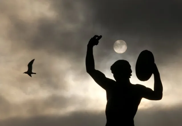 A seagull flies past a statue seen in silhouette at sunset in Marseille, France, November 6, 2015. (Photo by Jean-Paul Pelissier/Reuters)