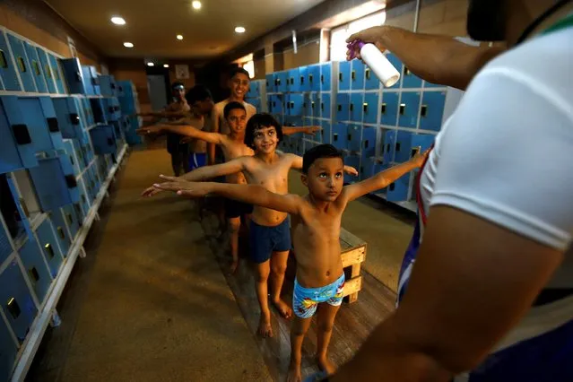 A man disinfects Iraqi children before using the swimming pool at Non-Government Organization-Mercy Among Them, amid the outbreak of the coronavirus disease (COVID-19), in the holy city of Kerbala, Iraq on October 20, 2020. (Photo by Alaa Al-Marjani/Reuters)