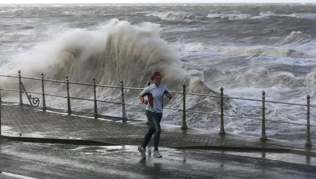 A woman runs past heavy seas on Blackpool Promenade, northern Britain, November 13, 2015.  Abigail, the first named storm to hit Britain, whipped up winds of up to 84 miles per hour and cut power to 12,000 home according to local media reports. (Photo by Phil Noble/Reuters)