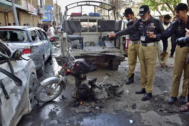 Police officers inspect the site of a bomb blast, in Quetta, Pakistan, Monday, April 10, 2023. A roadside bomb targeting a police vehicle in volatile southwestern Pakistan on Monday killed few people and wounded more than dozen others, mostly civilian pedestrians, a government spokesperson said. (Photo by Arshad Butt/AP Photo)