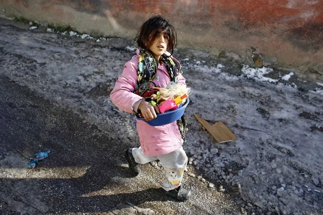A Syrian refugee girl carries a basin of toys she picked up from the debris of dismantled makeshift shelters of Syrian refugees, in the Hacibayram district of Ankara January 9, 2015. Authorities in Ankara on Friday rounded up more than three hundred Syrian refugees and tore down their temporary shelters in one of the poorest parts of the city. (Photo by Umit Bektas/Reuters)