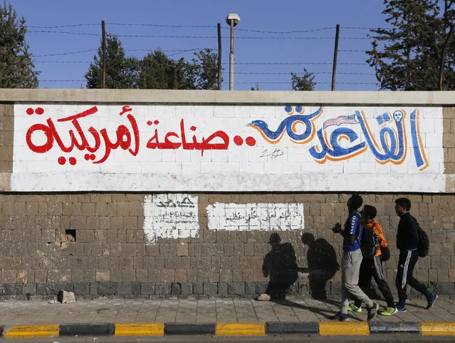 People walk past a graffiti reading “Al Qaeda is American-made” at the site of a recent car bomb attack in Sanaa January 14, 2015. (Photo by Khaled Abdullah/Reuters)