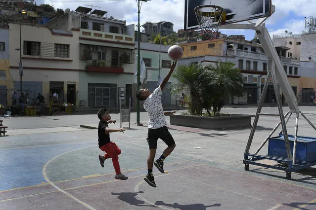 Children play a game of one on one on a public basketball court in the San Agustin neighborhood on Christmas Day in Caracas, Venezuela, Friday, December 25, 2020, amid the new coronavirus pandemic. (Photo by Matias Delacroix/AP Photo)