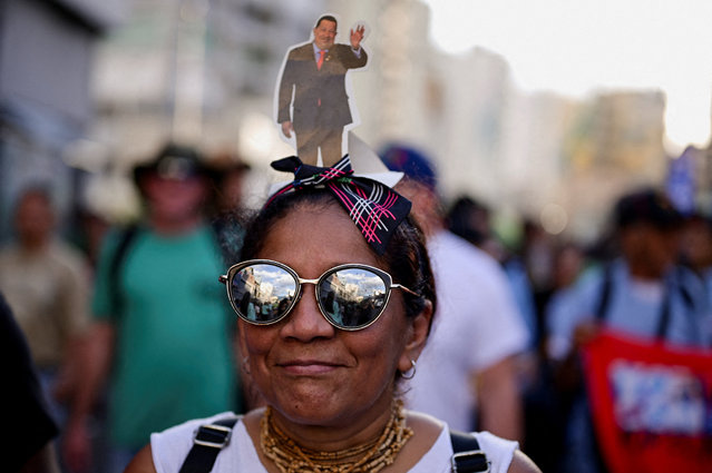 A supporter of Venezuelan President Nicolas Maduro wears a cutout image of late former President Hugo Chavez on her head during a rally amid rising tensions with the United States, in Caracas, Venezuela on October 30, 2025. (Photo by Gaby Oráa/Reuters)